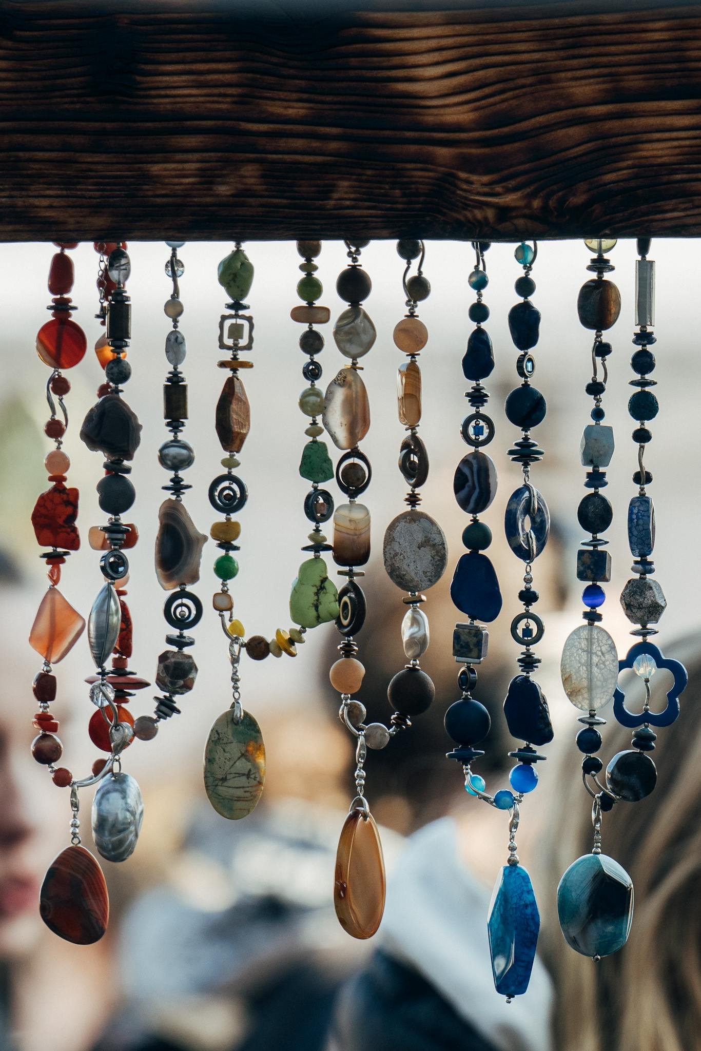A variety of handmade gemstone necklaces hanging at a market in Vilnius, showcasing vibrant colors.